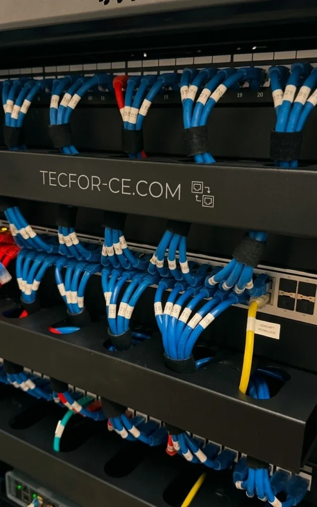 Close-up técnico de rack de rede com cabeamento estruturado azul organizado e alicate de crimpagem profissional em destaque.