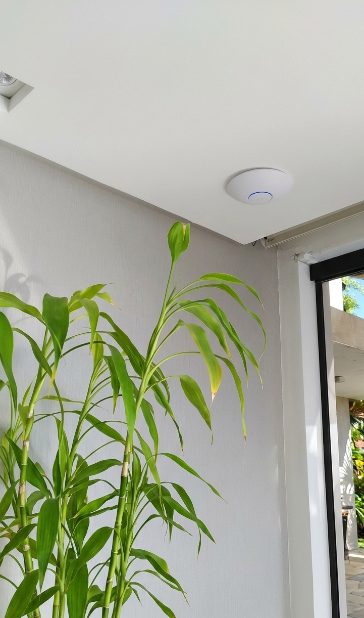 Ponto de acesso Wi-Fi circular instalado no teto de gesso, garantindo sinal de internet de alta performance com design discreto e elegante.
