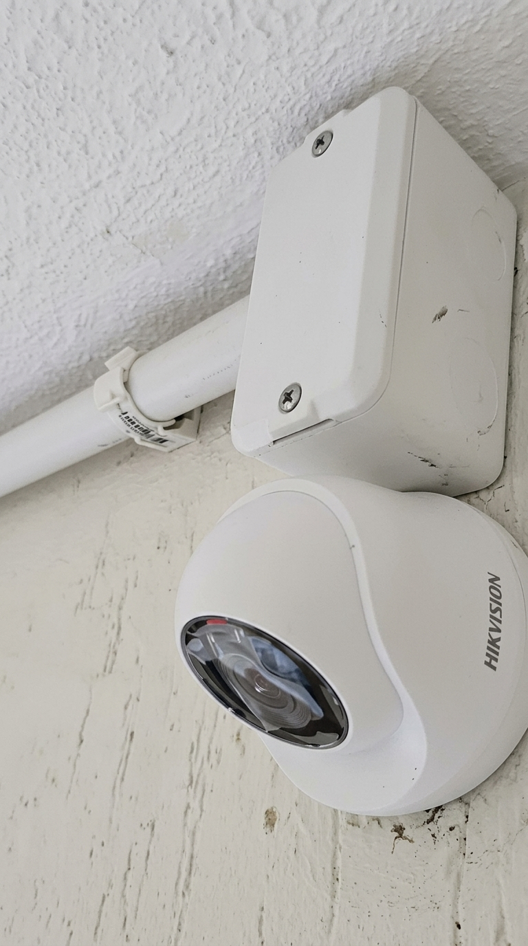 Câmera de segurança dome da marca Hikvision instalada na parede com caixa de passagem e tubulação aparente para CFTV.